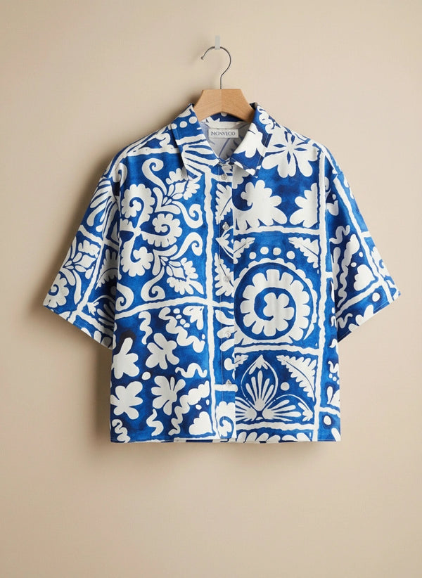 Blue and white patterned shirt on a hanger against a beige background