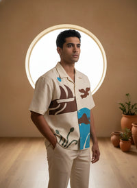 Man wearing a patterned shirt standing in a room with decorative elements.