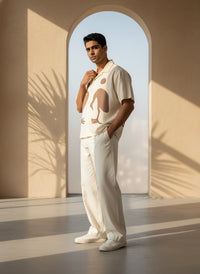 Man in a stylish outfit standing in a sunlit room with an archway.