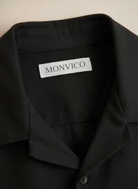 Black shirt with a Monvico label on a beige background