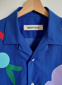 Blue shirt with colorful abstract designs on a hanger, featuring the brand 'MONVICO'.