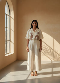 Woman wearing a white outfit with a pattern in a sunlit room