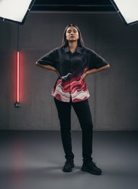 Person wearing a black and red outfit with a neon light in the background