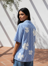 Woman wearing a blue checkered shirt with floral patterns outdoors.