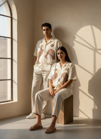 Two people wearing matching outfits sitting in a sunlit room.