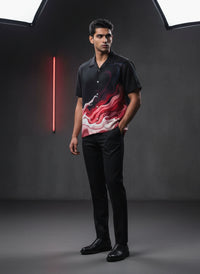 Man wearing a black shirt with a red and white design in a dark studio setting with neon light.