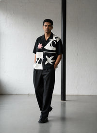 Man wearing a black shirt with abstract patterns in a minimalistic setting