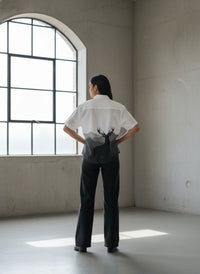 Person wearing a white shirt with a deer design in a minimalistic room.