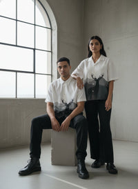 Two people wearing matching shirts with deer graphic designs in a minimalistic room.